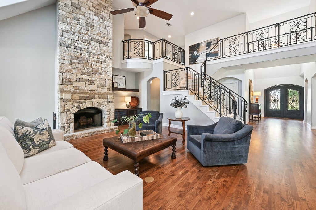 Spacious open living room featuring three levels and a petrified wood-effect stone fireplace, a floating spiral staircase ...