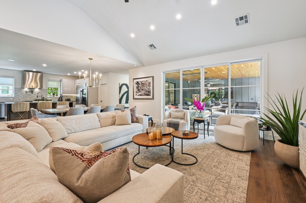 Living room interior with large windows, focusing on a seating area containing two couches and a small coffee table. A bed...