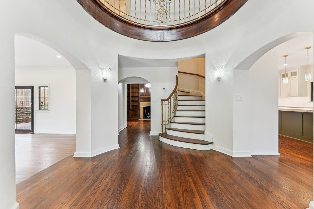The interior of a house, likely an old-style or traditional home, featuring a large arched doorway on either side, an arch...