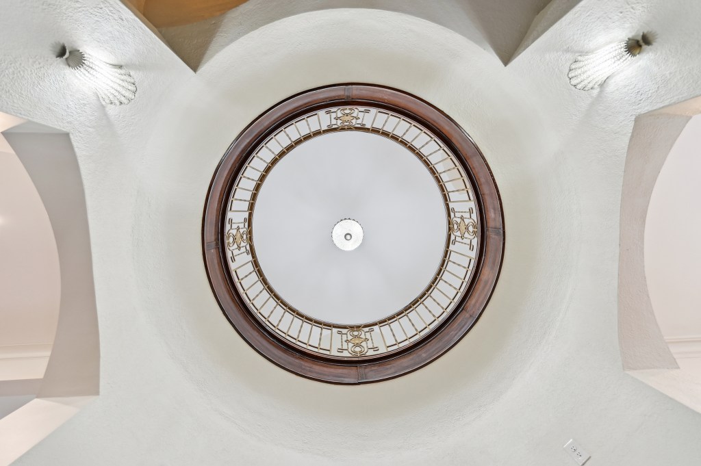 The ceiling in the image features a spacious round design centered by a white circular light feature with a brown bronze f...